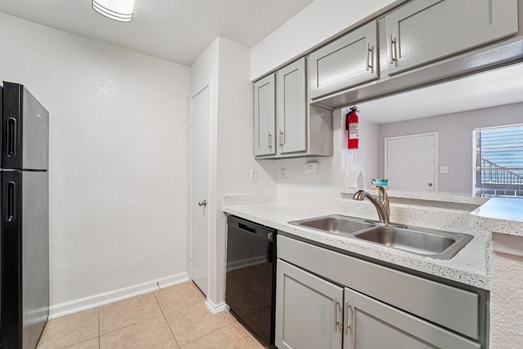 A kitchen with a black fridge and stainless steel appliances.