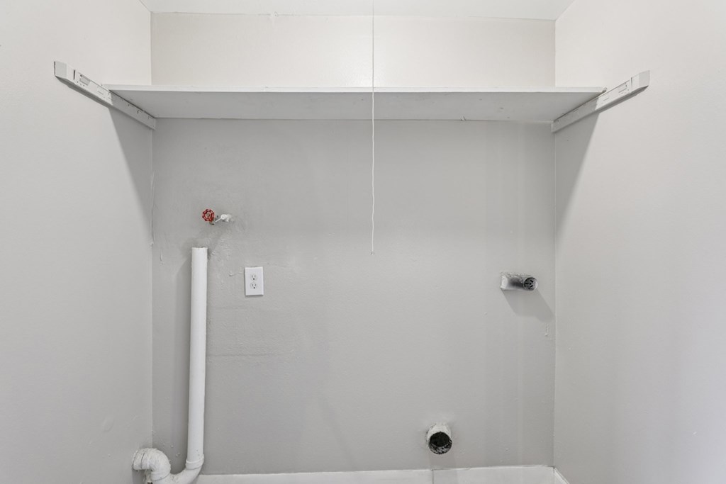 A white pipe runs along the wall under a shelf.