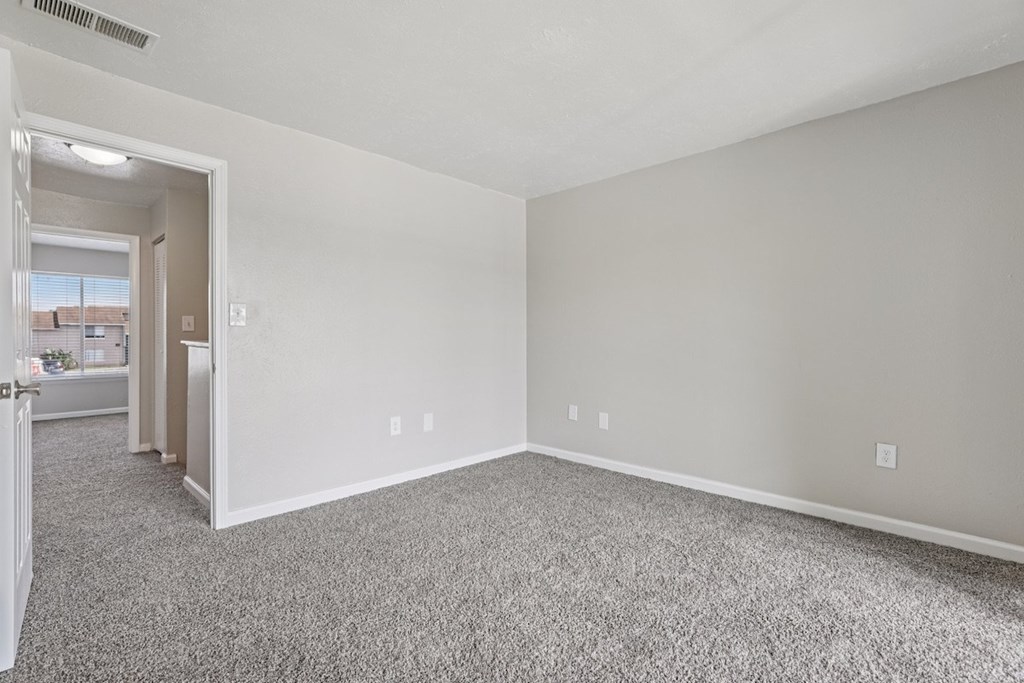 A large empty room with carpeted floor and white walls.