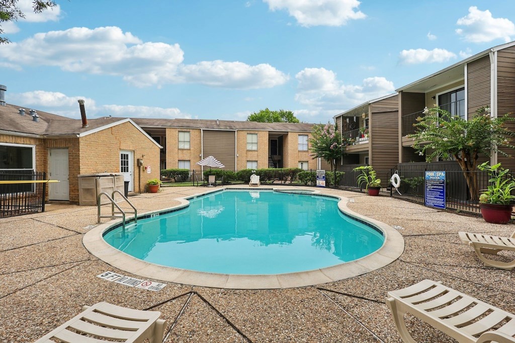 A small pool surrounded by a concrete patio and lounge chairs.