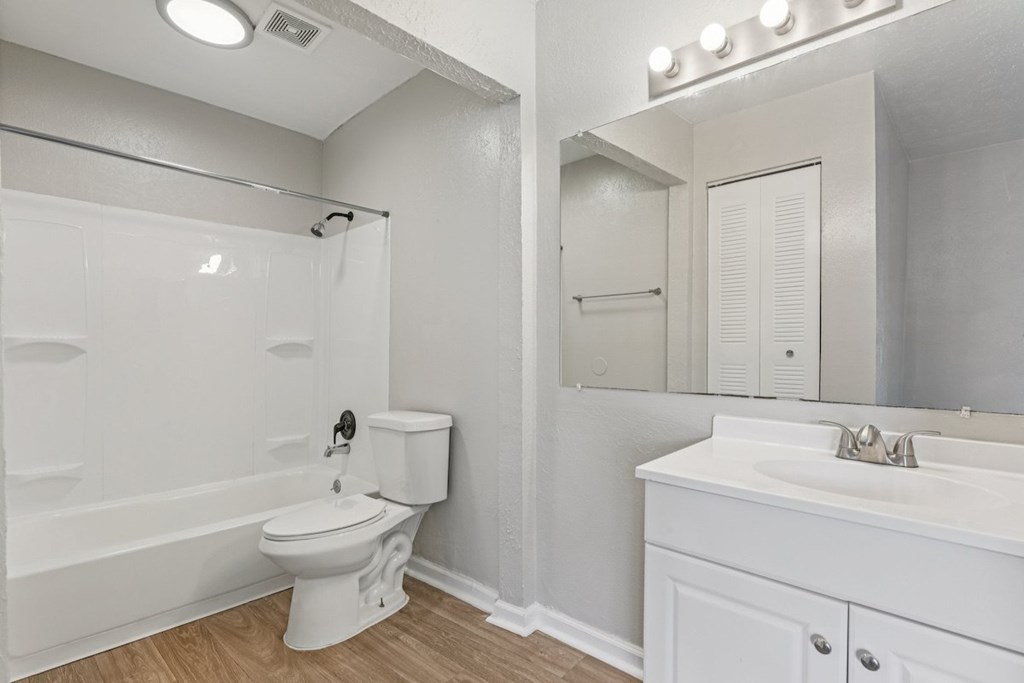 A white bathroom with a toilet, sink, and mirror.
