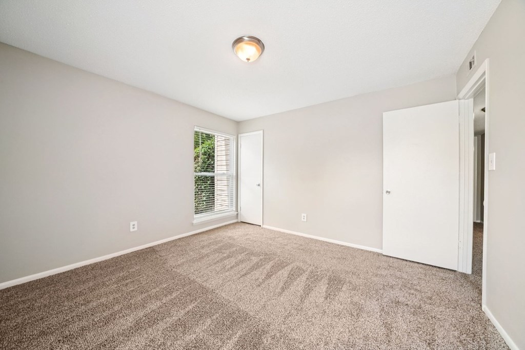 A room with a carpeted floor and a window with blinds.at Hills at Hoover Apartments, Hoover