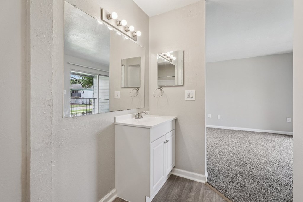 A bathroom with a white vanity and a large mirror.