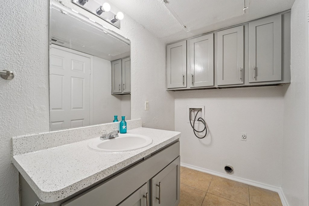 A bathroom with a sink, mirror, and cabinets.