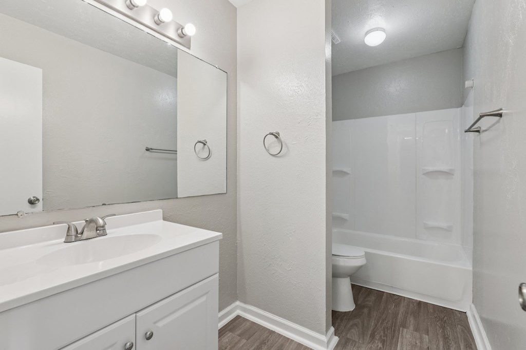 A white bathroom with a sink, mirror, and shower.