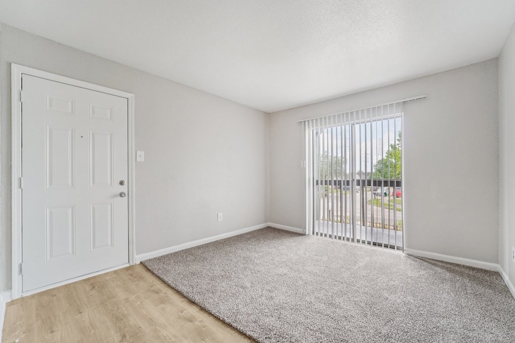 A room with a white door and a grey carpet.