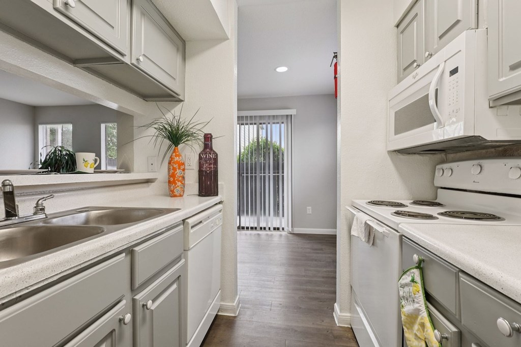 A kitchen with white cabinets and a stainless steel sink.