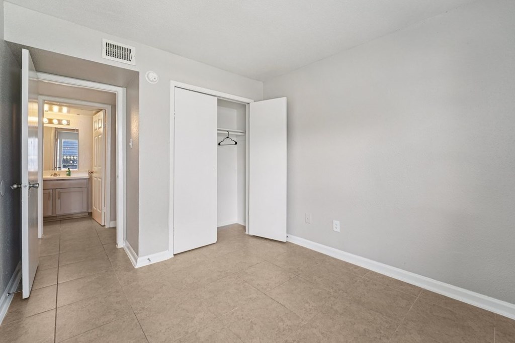 A room with a doorway leading to a kitchen and a hanger on the wall.