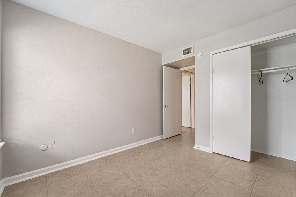 A room with a white door and a white closet with a hanger.