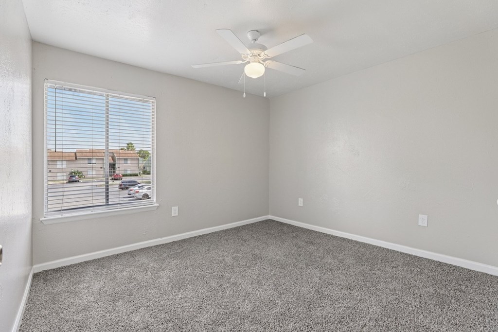 A room with a ceiling fan and carpeted floor.