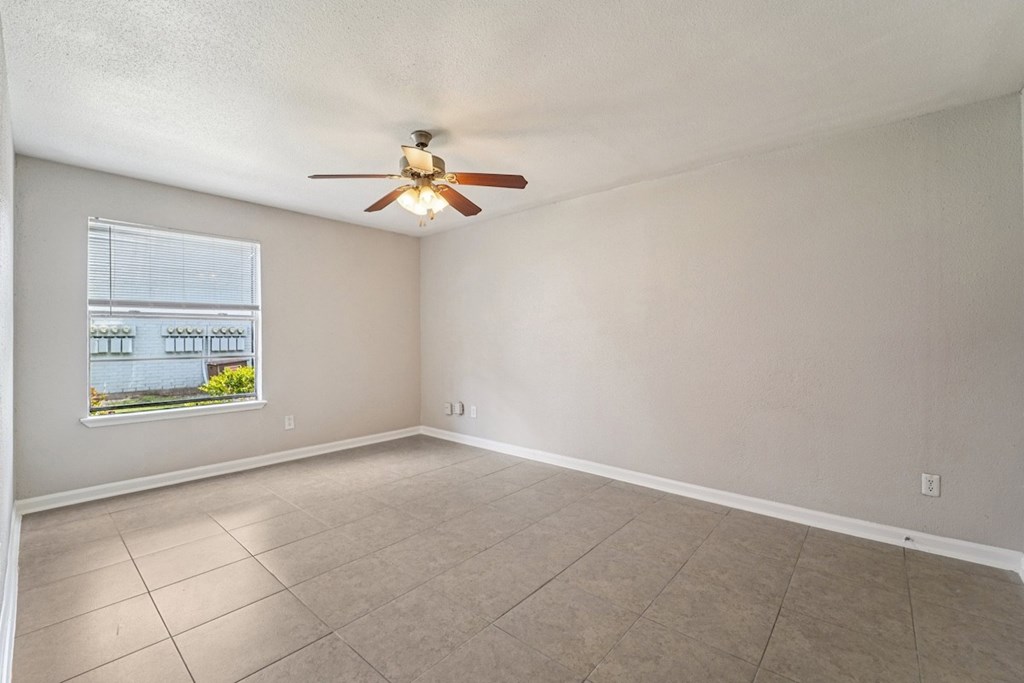 Empty room with a ceiling fan and a window.