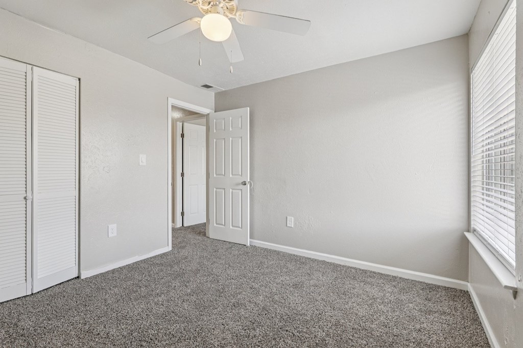 A room with a ceiling fan and carpeted floor.