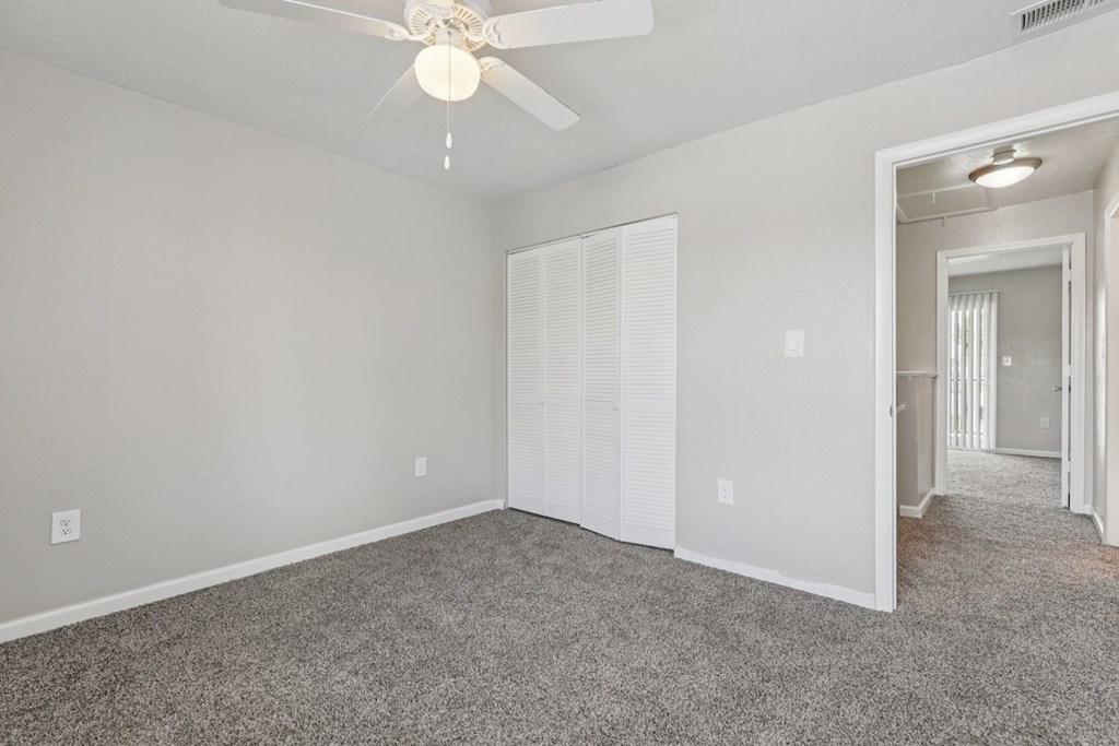 A room with a ceiling fan and carpeted floor.