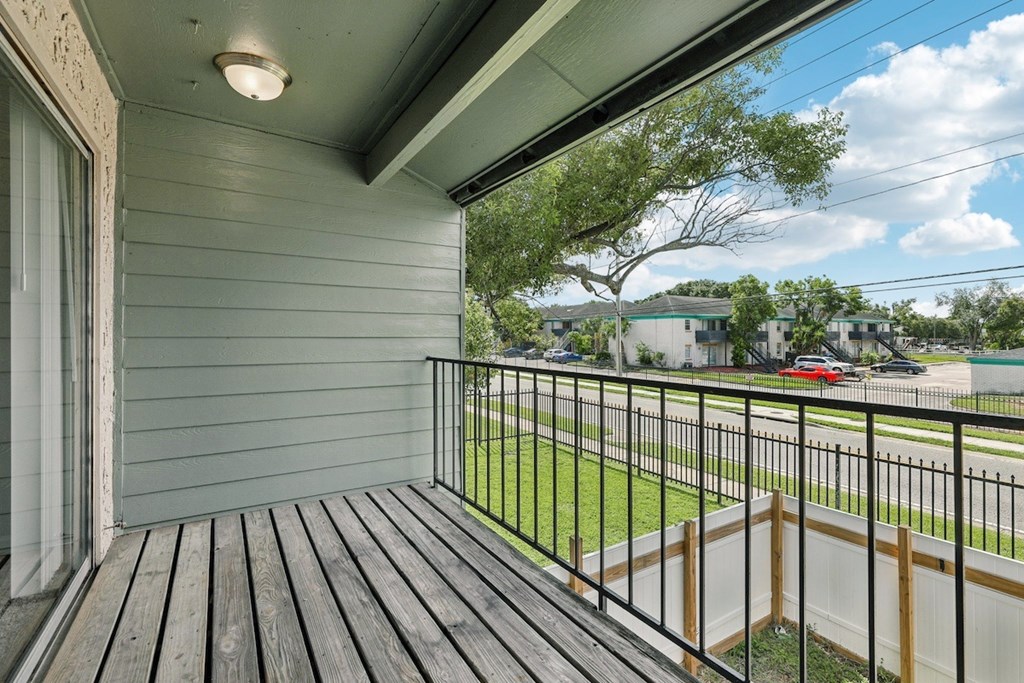 A balcony with a black railing and wooden floor.
