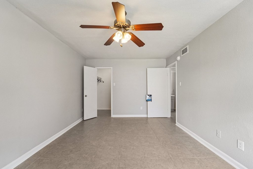 A room with a ceiling fan and two doors.