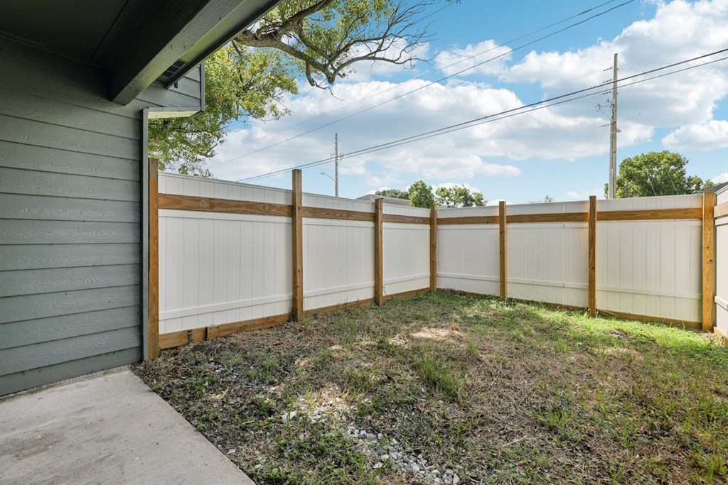 A backyard with a wooden fence and a grey house.