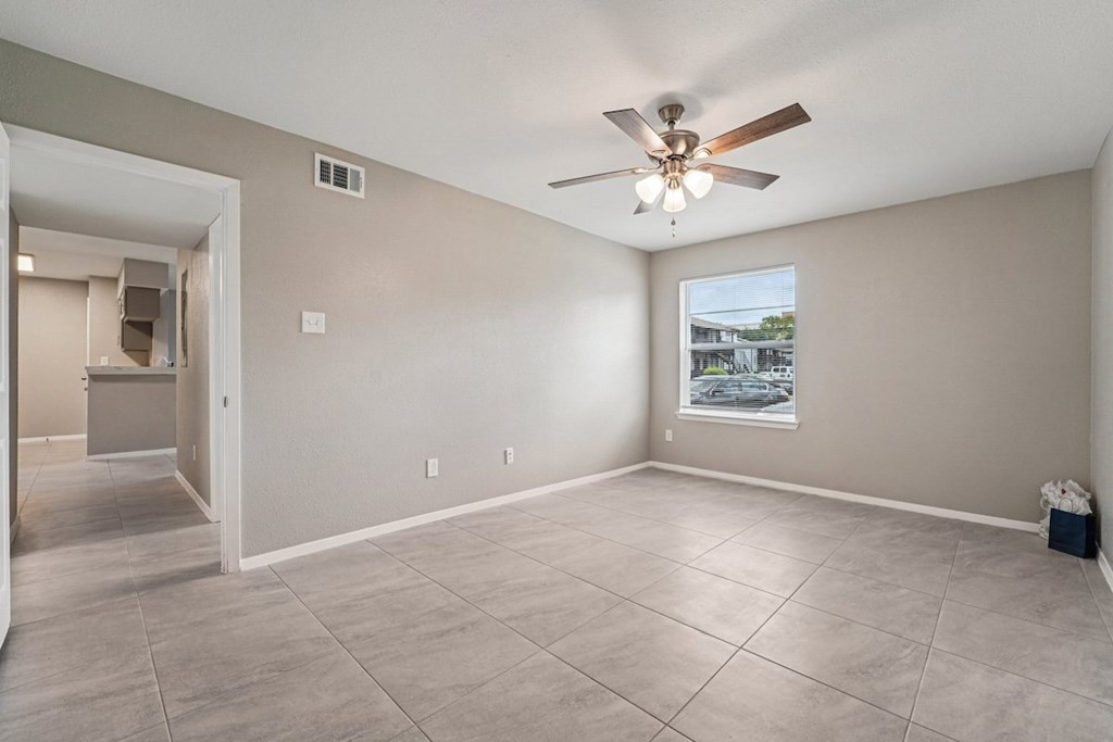 A room with a ceiling fan and a window showing a view of a building outside.