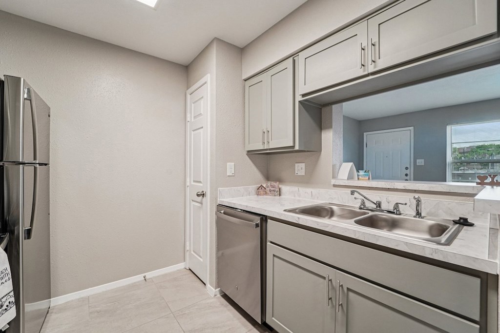 A kitchen with a refrigerator, sink, and cabinets.