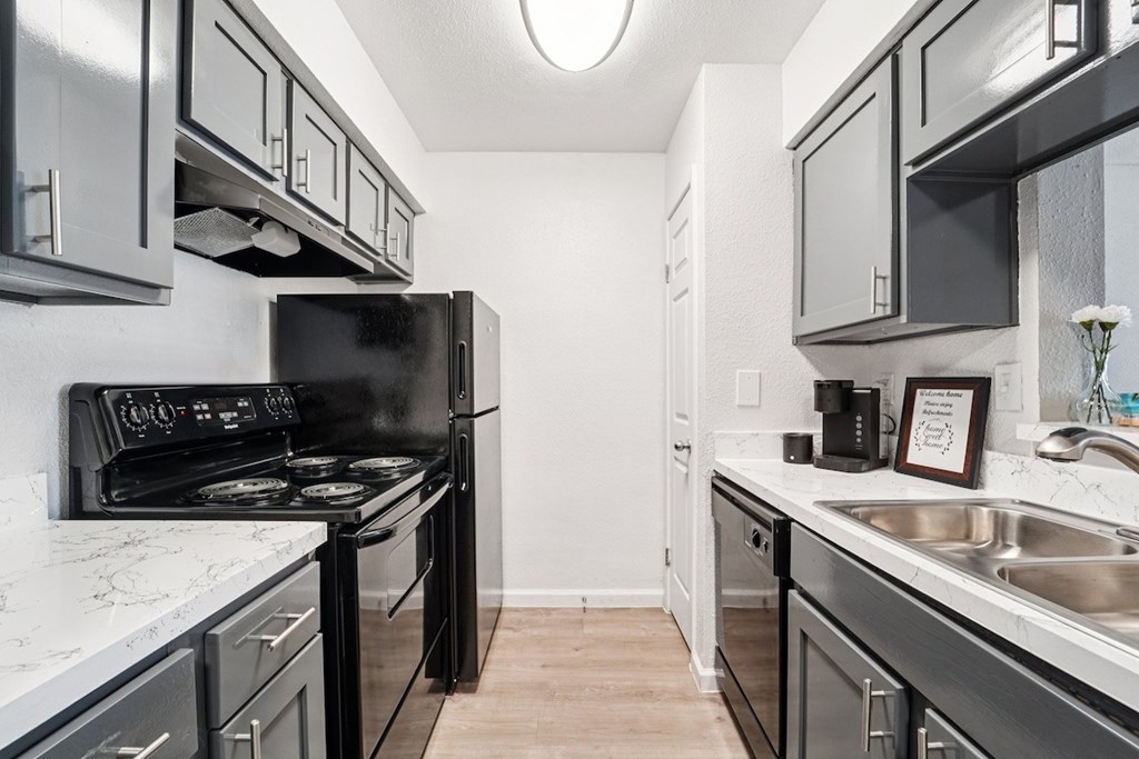 A kitchen with black appliances and white countertops.