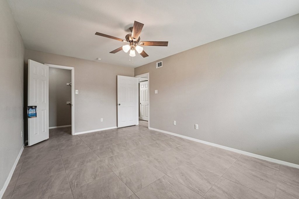 A room with a ceiling fan and tile flooring.