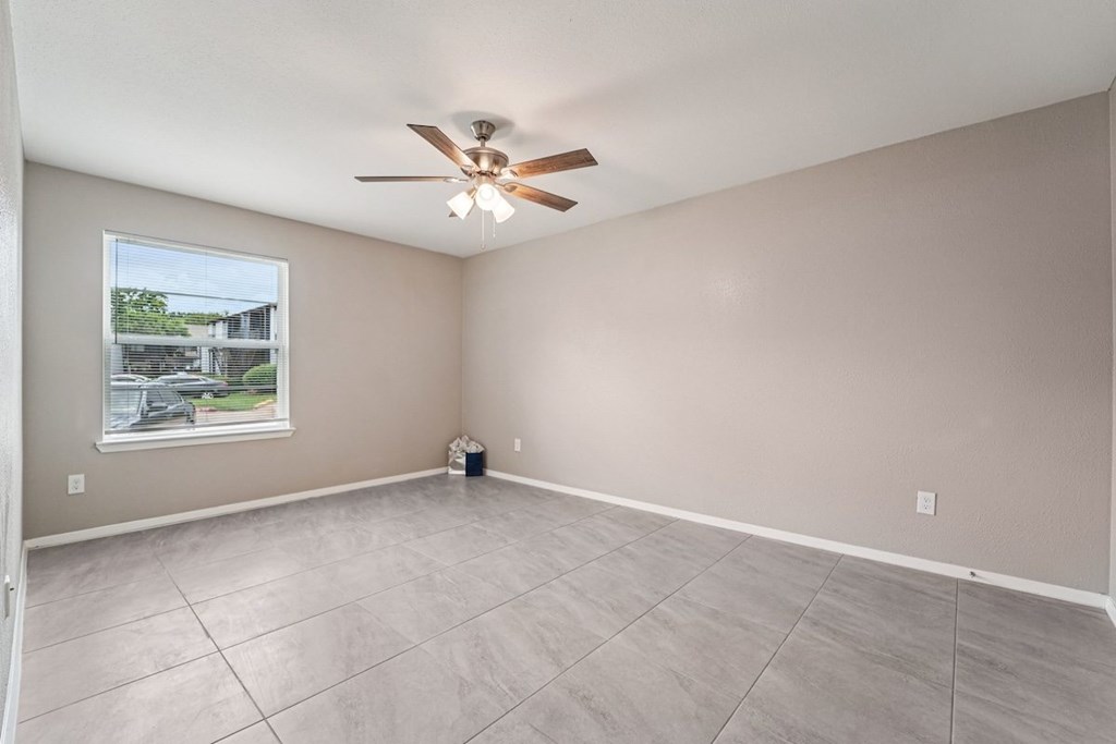 A room with a ceiling fan and a window showing an outdoor view.