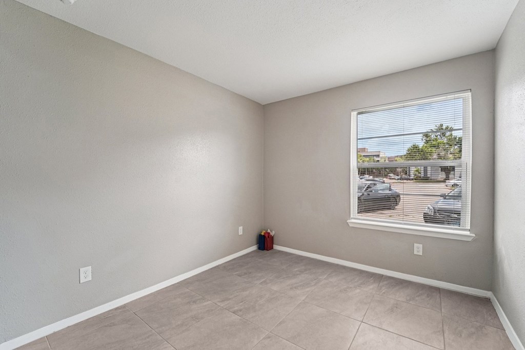 A room with a large window showing a parking lot outside.