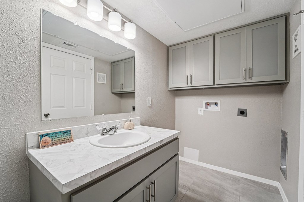 A bathroom with a sink, mirror, and cabinets.