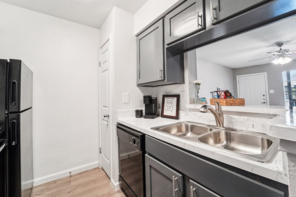 A kitchen with a black refrigerator and a white sink.