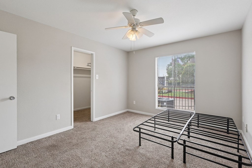 A bedroom with a metal frame bed and a ceiling fan.