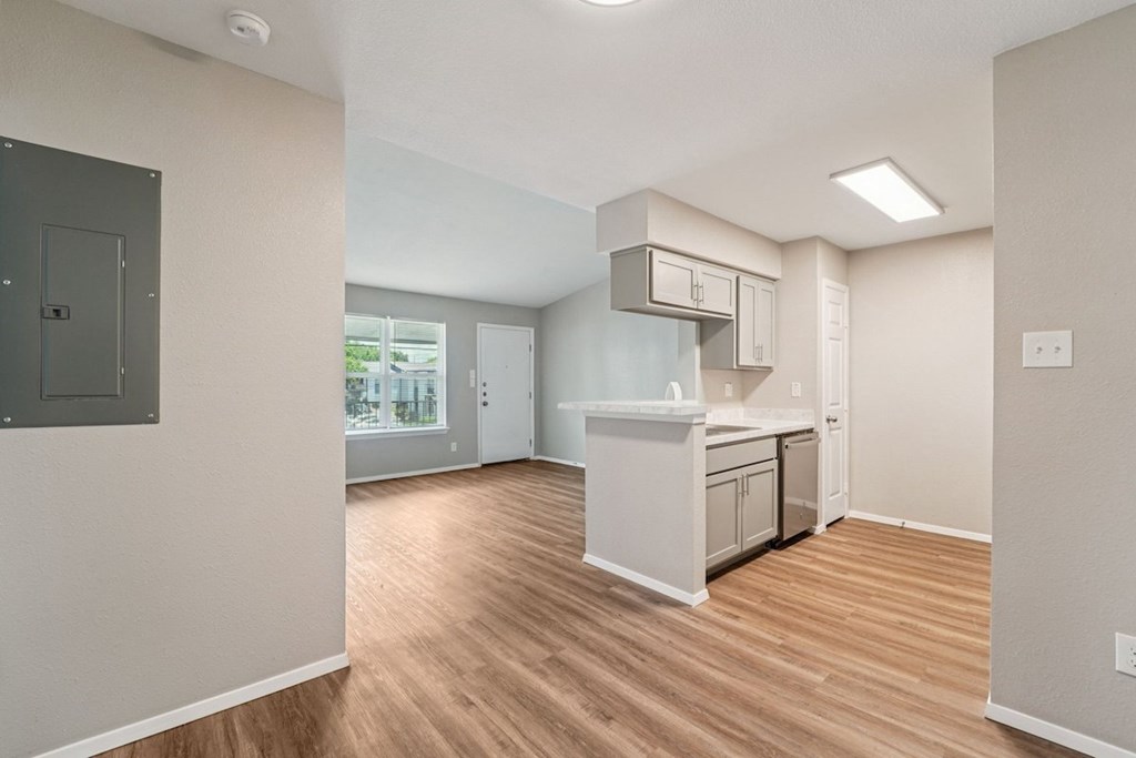 A kitchen area with a white countertop and wooden flooring.