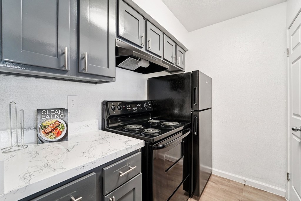 A kitchen with black appliances and a book titled Clean Eating on the counter.