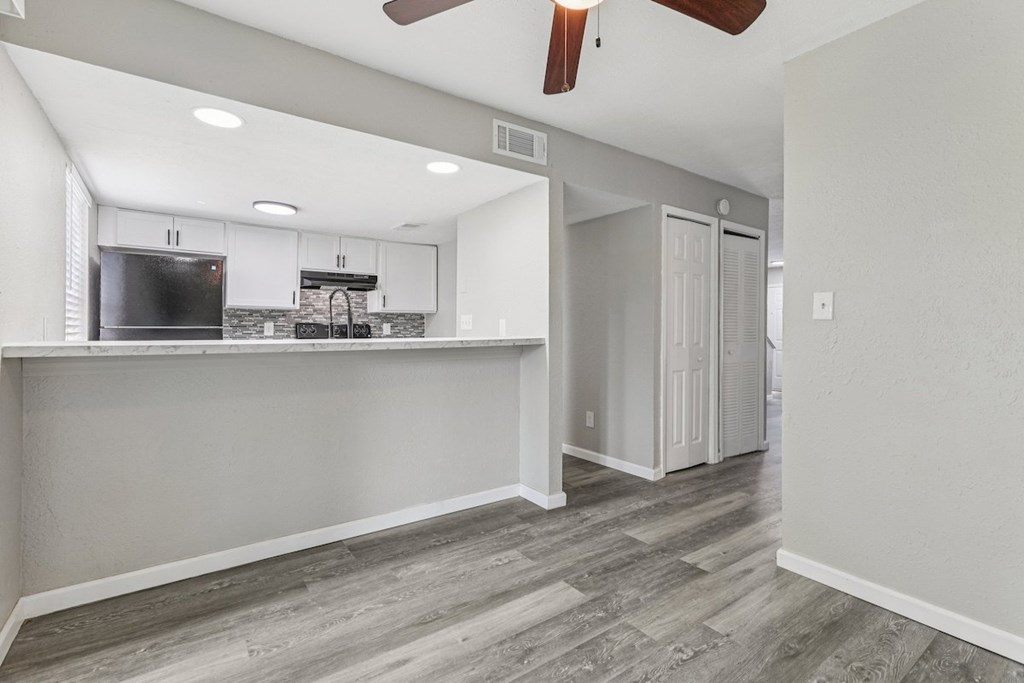 A kitchen area with a refrigerator, sink, and cabinets.