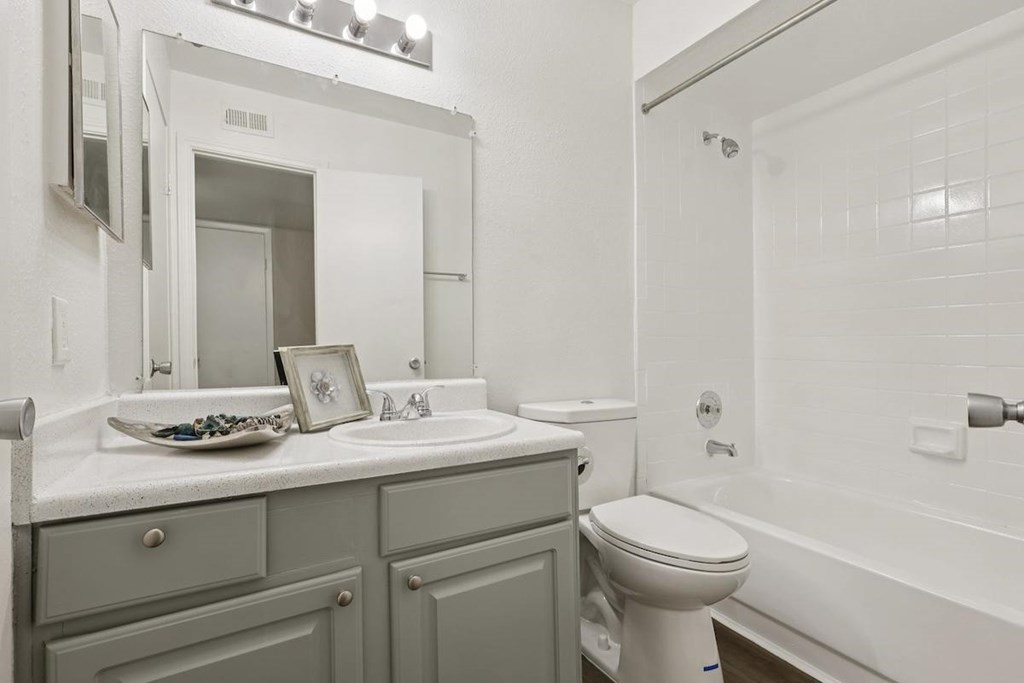 A white bathroom with a toilet, sink, and mirror.