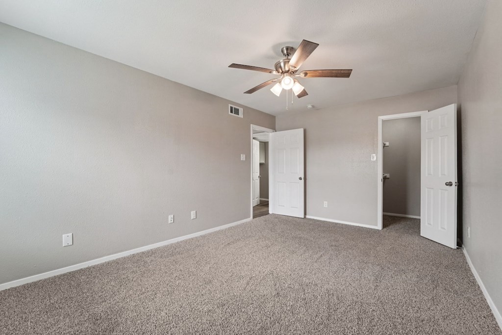 A room with a ceiling fan and carpeted floor.
