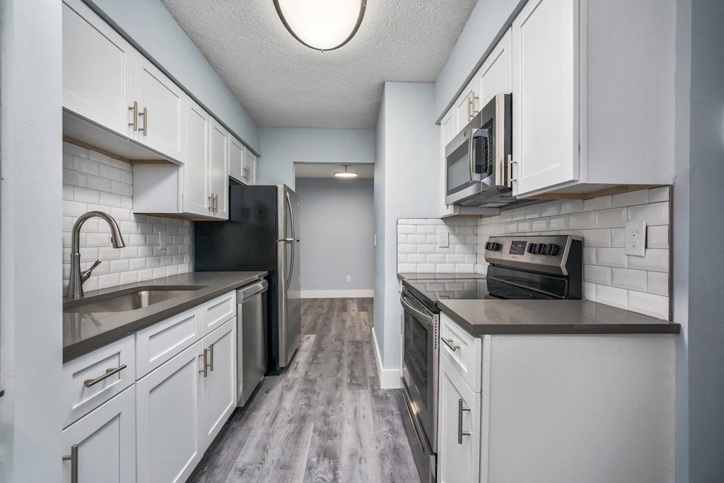 an empty kitchen with white cabinets and a black stove and refrigerator at Ascot Place Apartments, Birmingham, AL