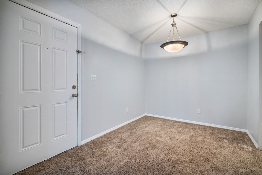 an empty room with carpet and a white door at Ascot Place Apartments, Birmingham Alabama