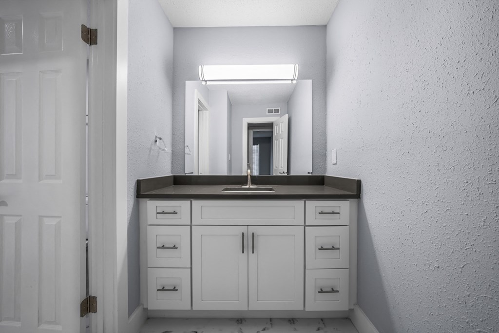 a white bathroom with a sink and a mirror at Ascot Place Apartments, Birmingham, AL 35235