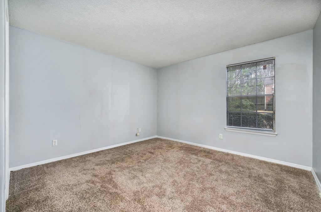 an empty room with carpet and a window at Ascot Place Apartments, Birmingham, AL