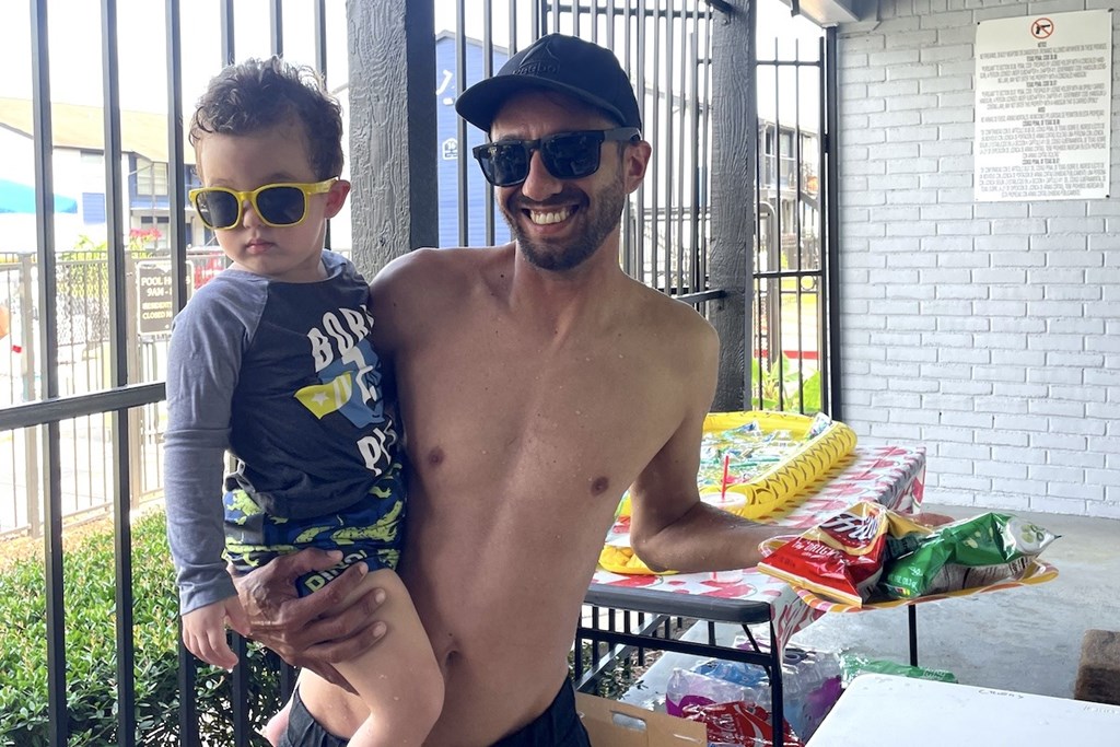 A man and a child are standing in front of a table with snacks on it.