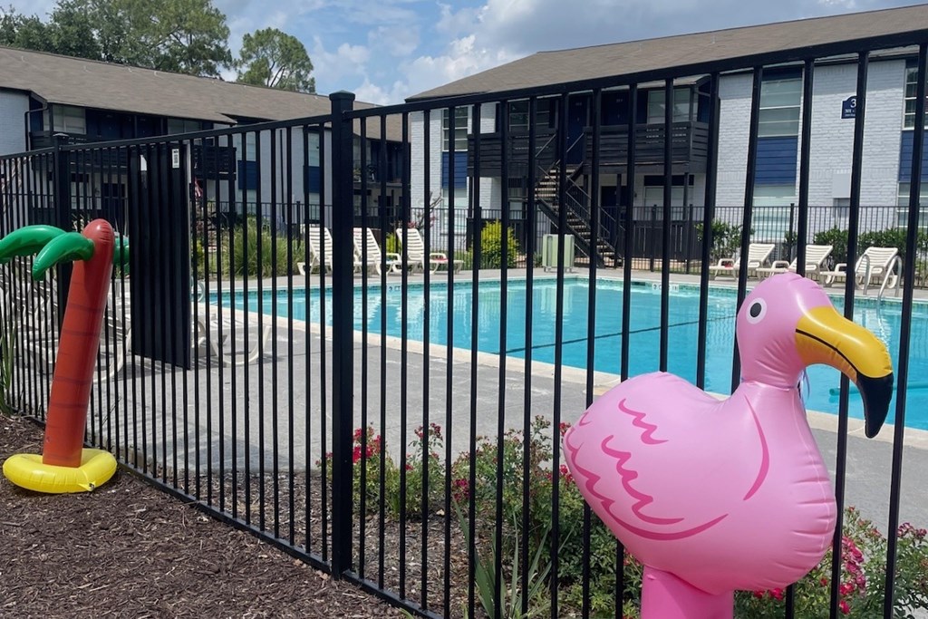 A pink flamingo statue stands next to a pool.