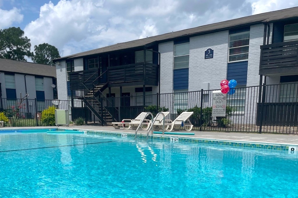 A pool with chairs and a balloon in front of a building.