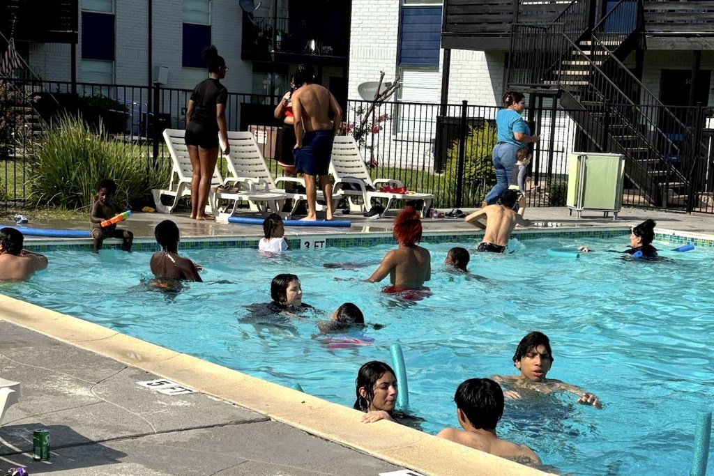 A group of people are in a pool on a sunny day.