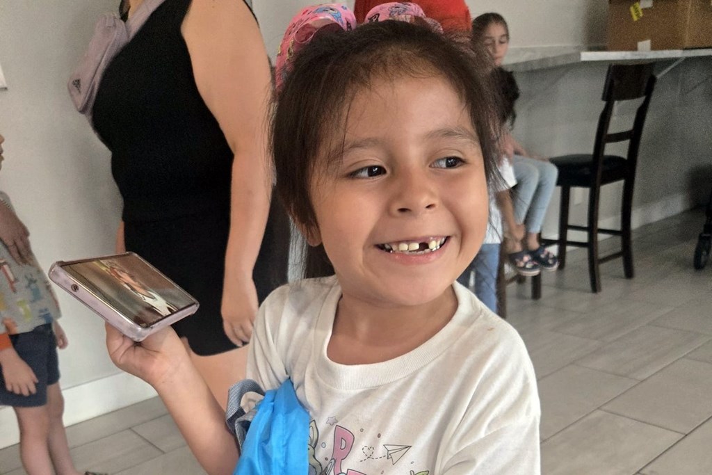 A young girl is holding a book and smiling.
