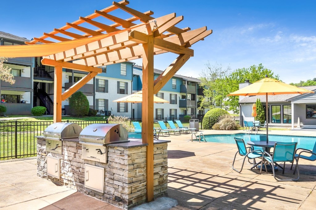 a backyard with a pool and a picnic table with umbrellas a backyard with a pool and a picnic table with umbrellas at Crestwood Green Apartments, Birmingham Alabama