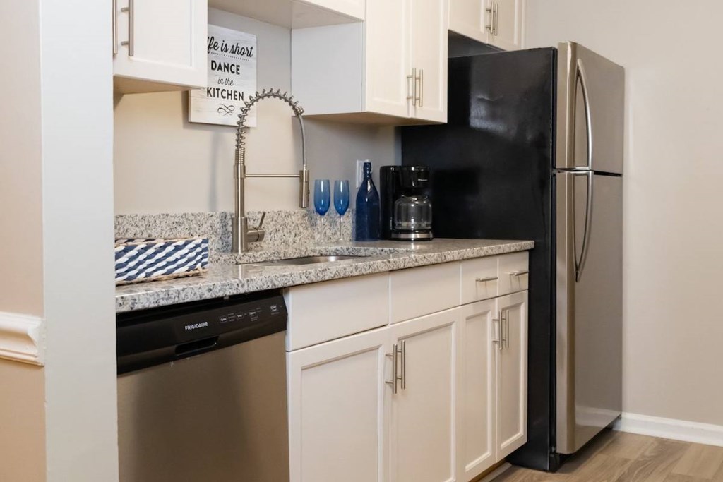 a kitchen with white cabinets and a stainless steel refrigerator a kitchen with white cabinets and a stainless steel refrigerator at Crestwood Green Apartments, Birmingham, AL
