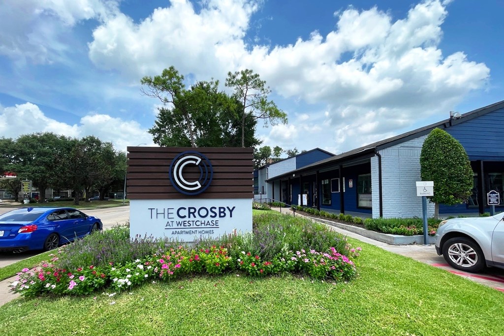 The Crosby at Westchase Apartment Community is a modern apartment complex with a well-maintained garden in front.
