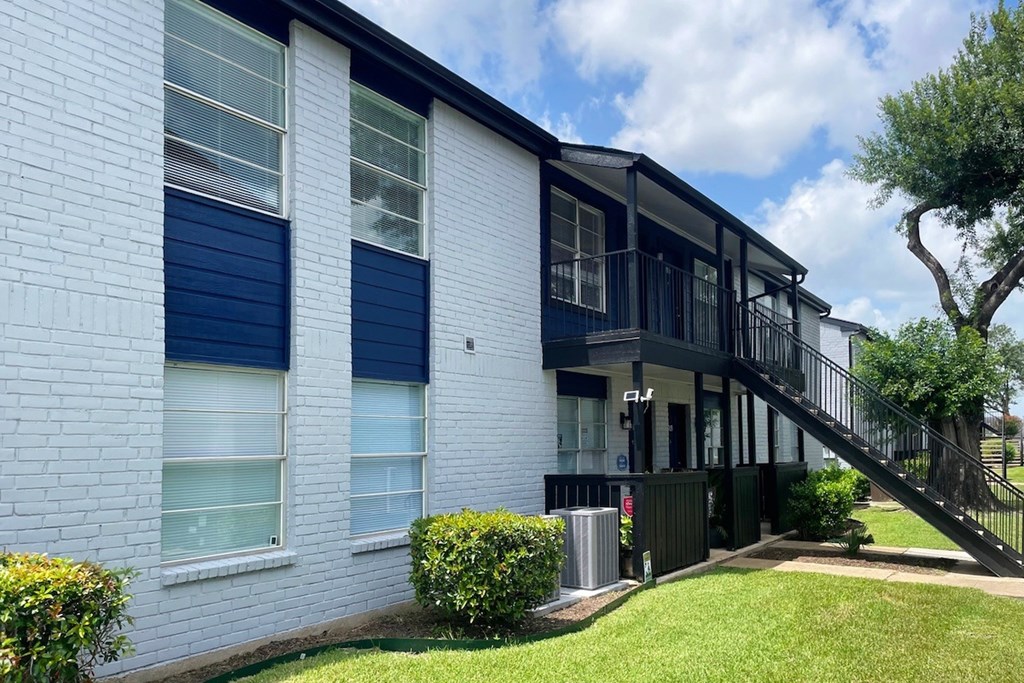 A white house with blue shutters and a black railing.