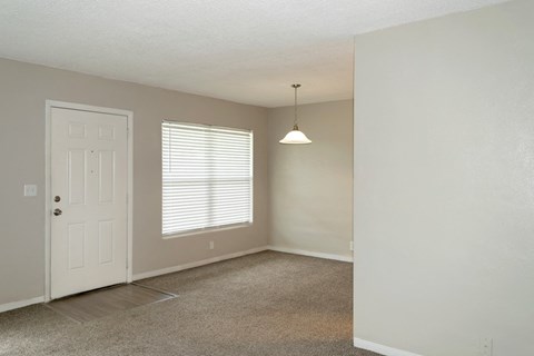 an empty living room with a white door and window