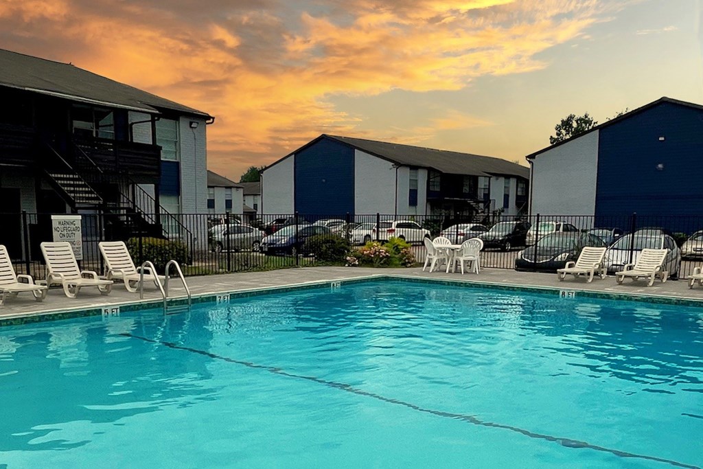 A swimming pool surrounded by chairs and buildings.