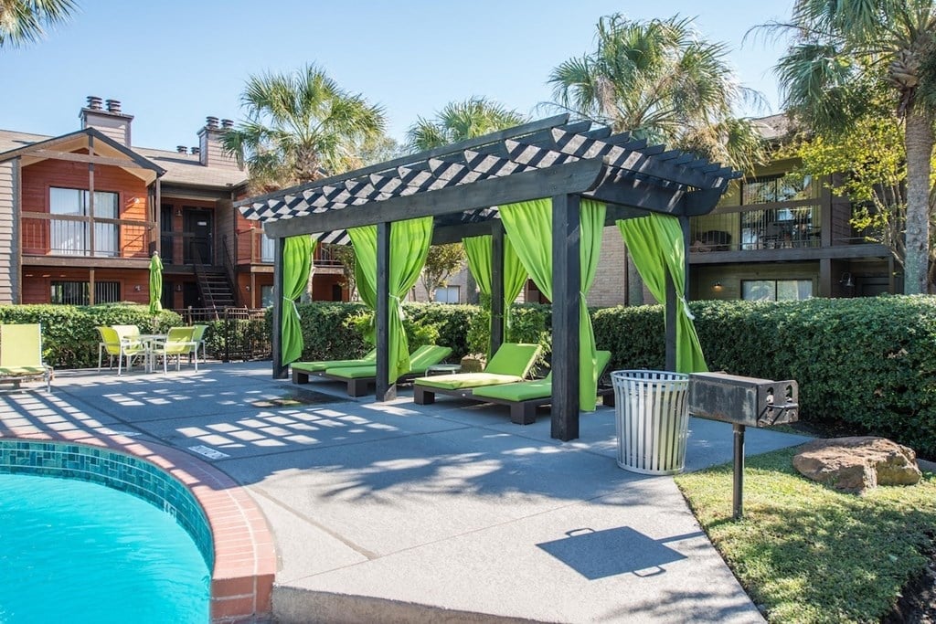 a pergola with loungers, and curtains, and a poolside grill at Hudson at Westchase